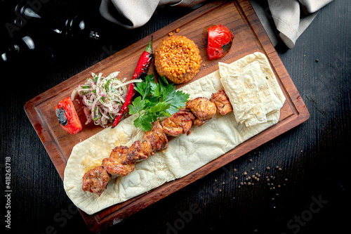 Chicken kebab cooked on the grill with lavash, bulgur and grilled vegetables on a wooden board. Turkish kebab. Close up ,selective focus