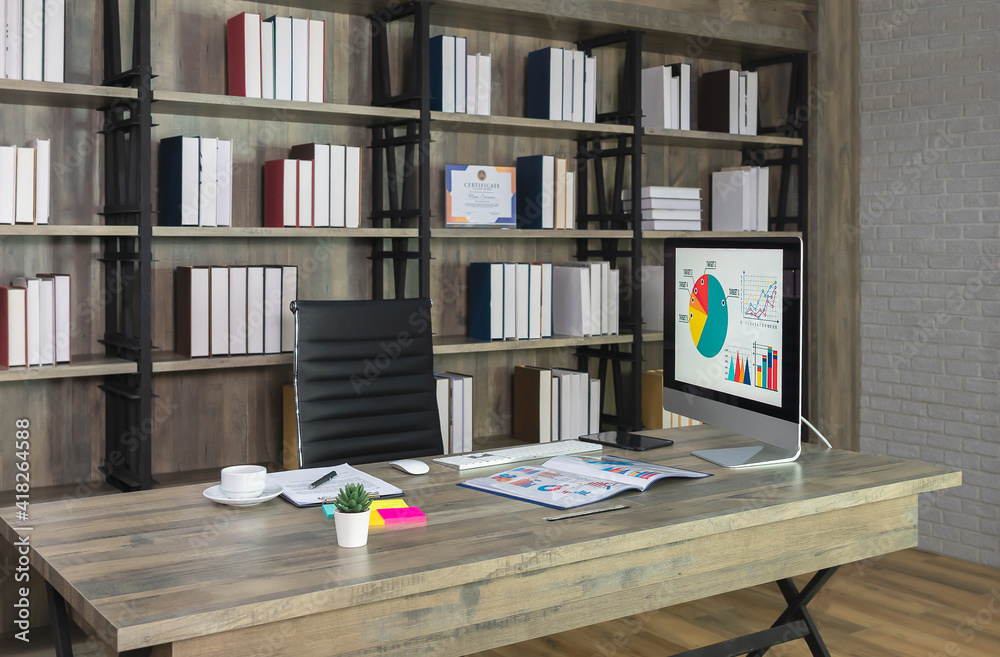 Workspace with desktop computer on wooden desk and black chair with bookshelf on the background. Workspace with desktop computer on wooden desk and black chair with bookshelf on the background.