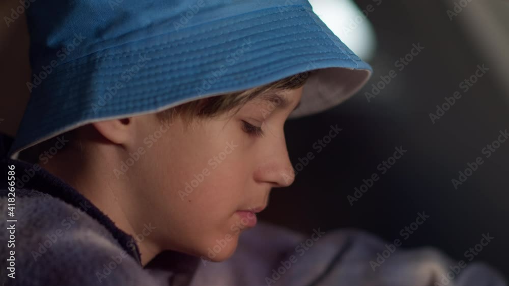 profile of a serious sad boy in a blue hat thinking about something in an abandoned house