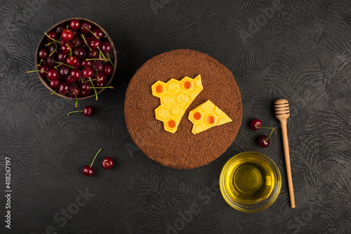 Honey cake with cherries on a black background. Top view with a copy space for the text.