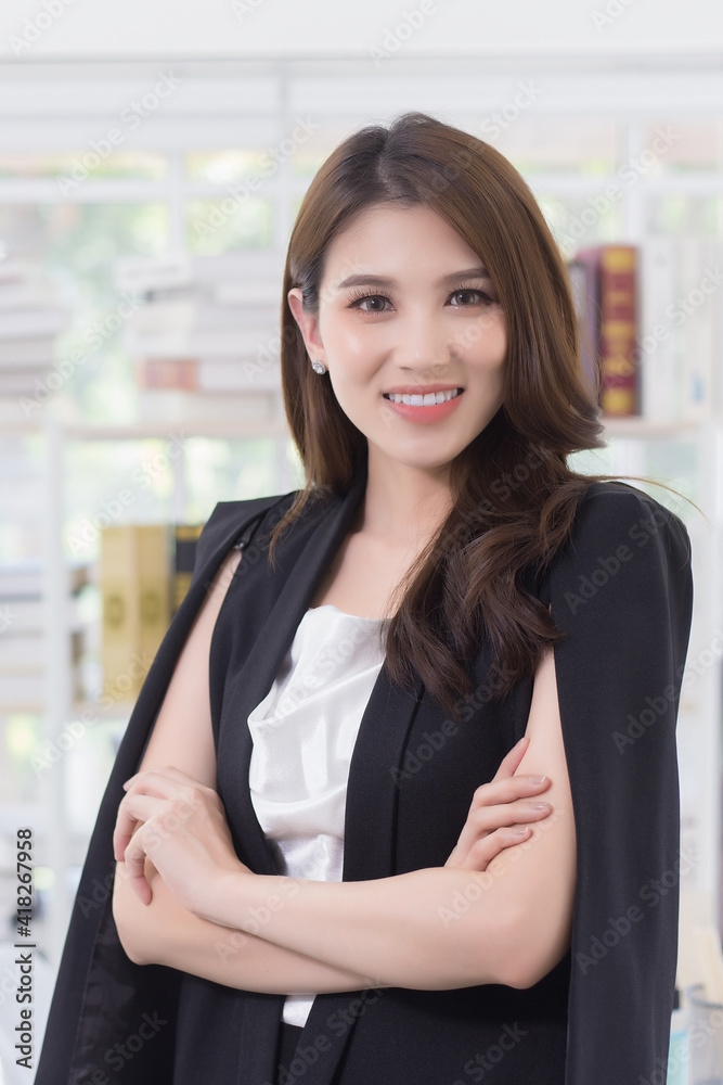 Work from home. Beautiful office lady standing and smiling at work happily. She is a successful Asian businessman. Work from home. Beautiful office lady standing and smiling at work happily. She is a successful Asian businessman.