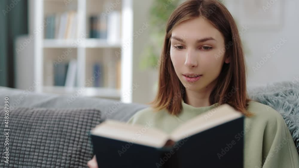 Excited woman sitting on comfy couch and reading fascinating book. New literature with interesting plot. Leisure time at home. Excited woman sitting on comfy couch and reading fascinating book. New literature with interesting plot. Leisure time at home.