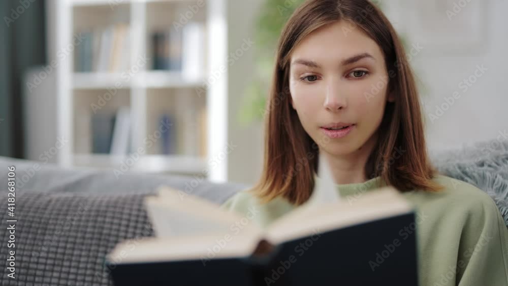 Portrait of pleasant young woman reading new interesting book at home. Happy brunette relaxing on cozy sofa with literature in hands. Portrait of pleasant young woman reading new interesting book at home. Happy brunette relaxing on cozy sofa with literature in hands.