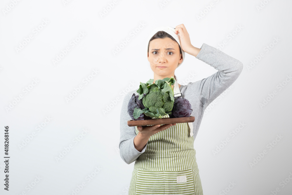 Shot of young cook holding plate of cabbage and broccoli on white background Shot of young cook holding plate of cabbage and broccoli on white background