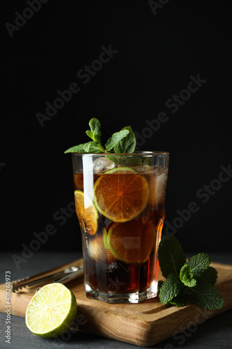 Board with glass of Cuba Libre against dark background