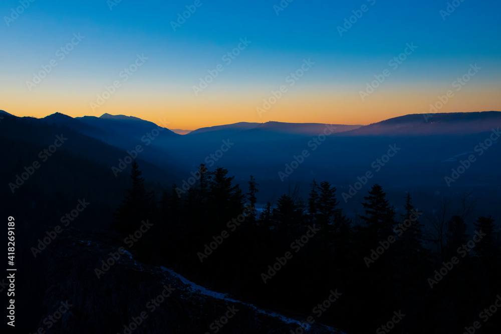 Colorful evening sky over Zakopane town, Poland. The winter is coming to the mountains. Clear sky filled with bright and vibrant colors. Selective focus on a mountain ridge, blurred background.