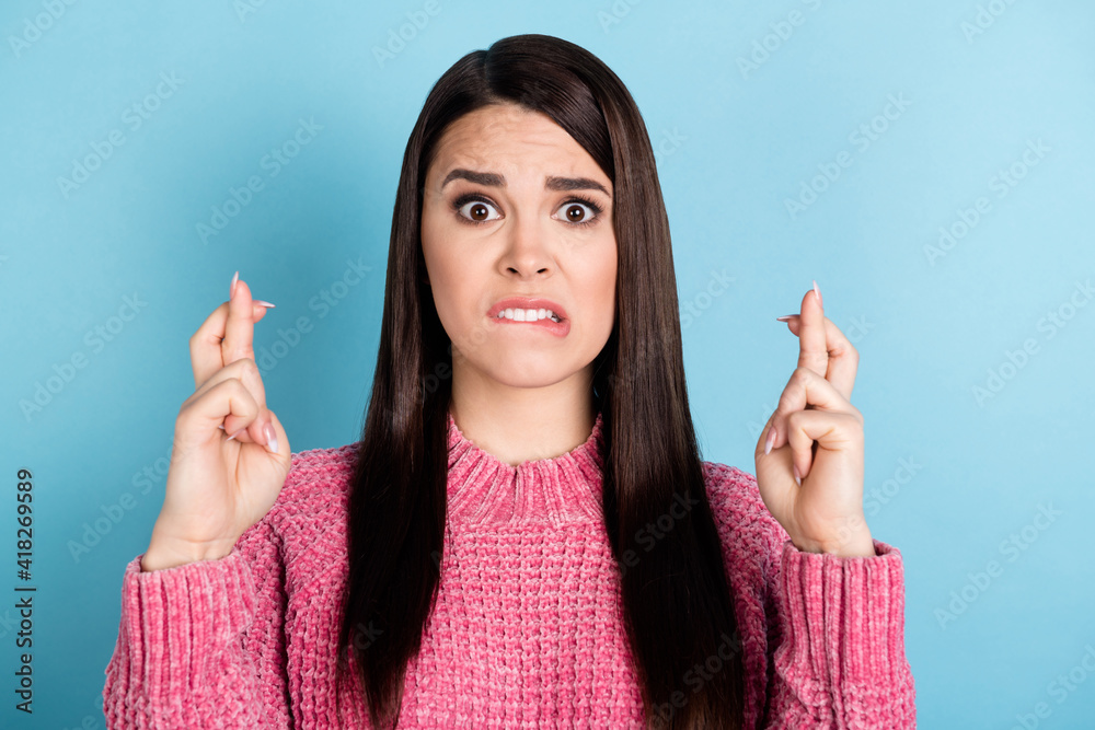 Photo of questioned young girl biting lip crossed fingers look camera wear sweater isolated on blue color background Photo of questioned young girl biting lip crossed fingers look camera wear sweater isolated on blue color background
