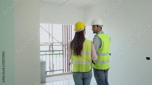Builder caucasian, asian contractor, engineer man and woman discussing, explain and inspecting material,wearing helmets in construction building, apeamwartment at site.Industrial tork concept. photo