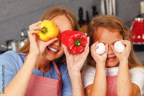 Mother and daughter having fun with food while cooking in kitchen