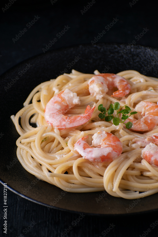 Pasta with shrimps on a black plate. Close-up