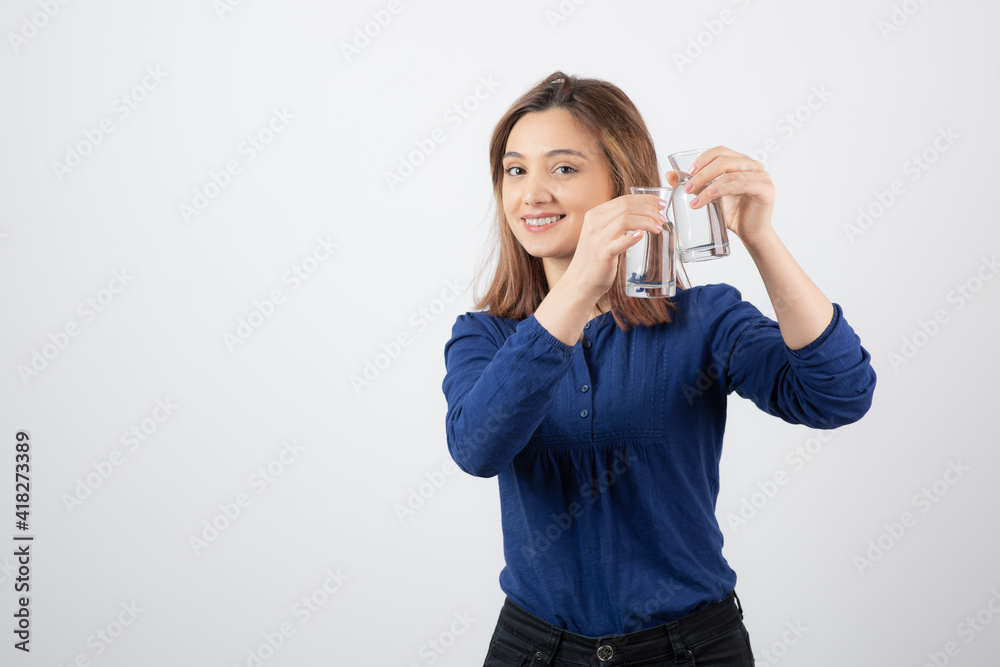 Beautiful woman in blue blouse holding glass of water on white background Beautiful woman in blue blouse holding glass of water on white background