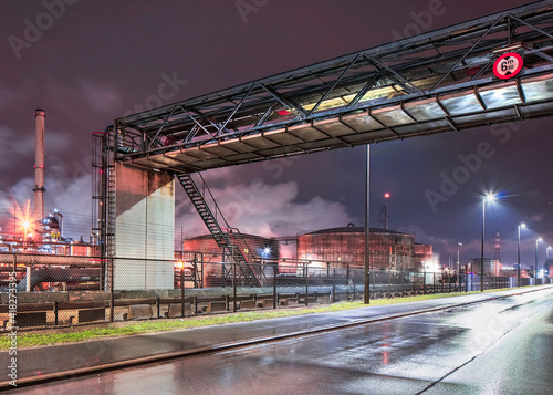 Tela Rainy night scene with pipeline overpass at petrochemical production plant, port of Antwerp, Belgium