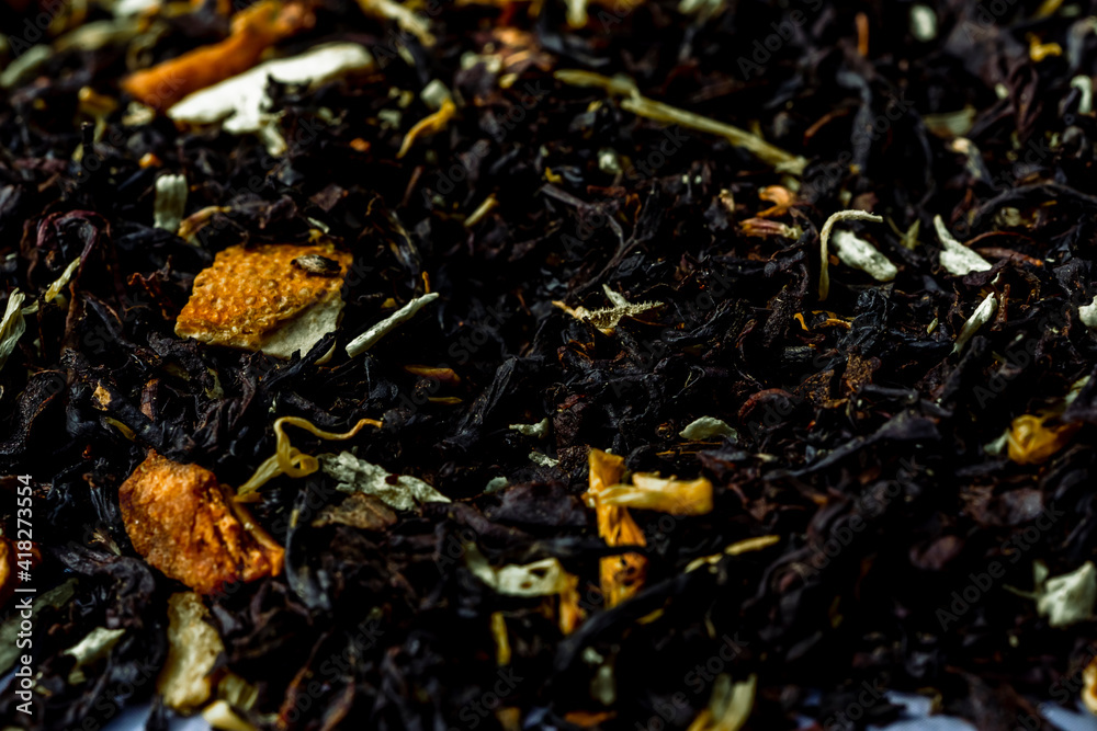 Dry black tea leaves with pieces of dried citrus peel, fruit and flowers. Close up tea background background.