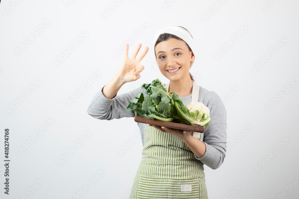 Picture of a smiling attractive woman with a wooden plate of cauliflowers Picture of a smiling attractive woman with a wooden plate of cauliflowers