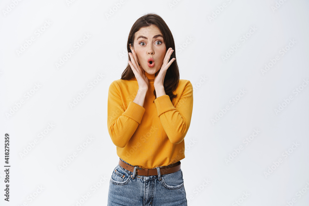 Excited young woman hear big news, say wow and stare amazed at camera, checking out advertisement, seeing awesome promo offer, white background