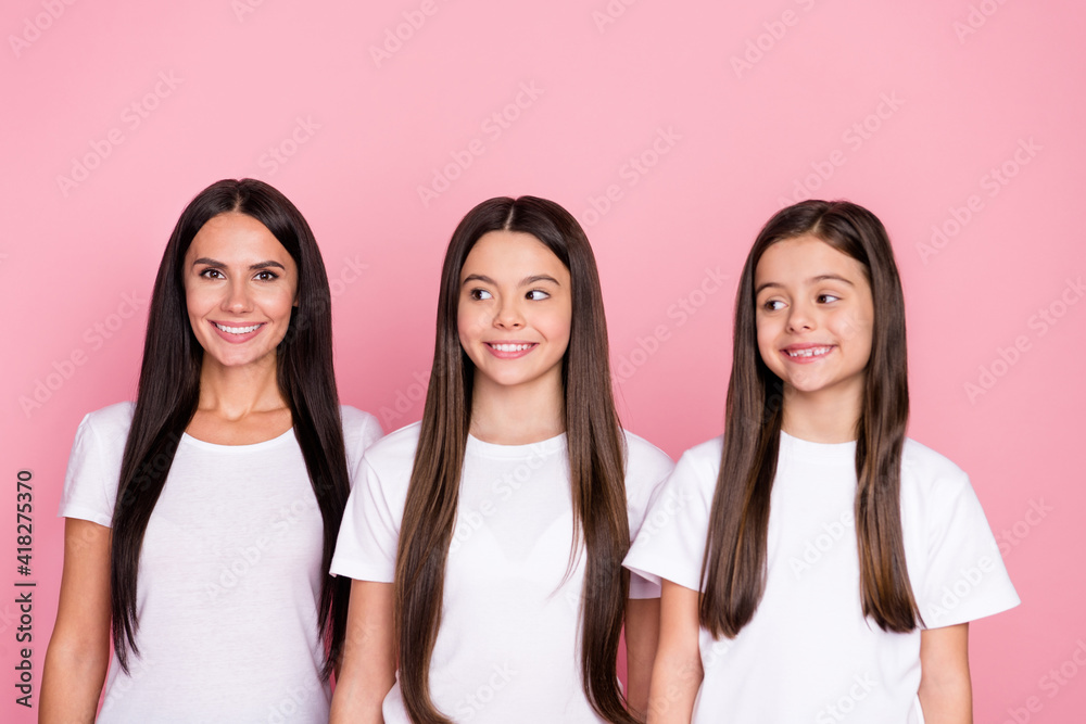 Photo portrait of smiling happy mother and daughters looking empty space wearing casual clothes isolated pastel pink color background Photo portrait of smiling happy mother and daughters looking empty space wearing casual clothes isolated pastel pink color background
