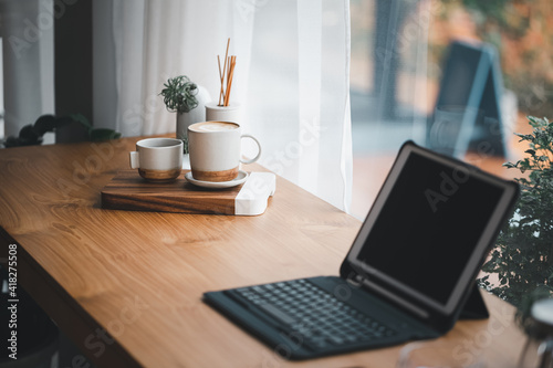 cup of hot coffee and tea on table with blurred tablet