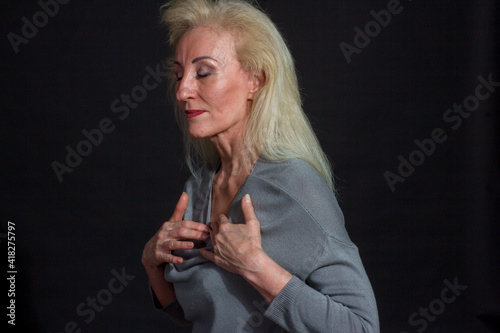 Classic dramatic portrait of elderly blonde woman in Studio on black background