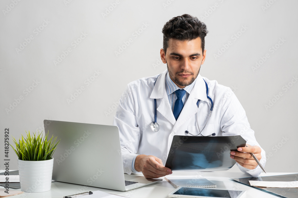 Handsome young doctor looking at x-ray scan Handsome young doctor looking at x-ray scan