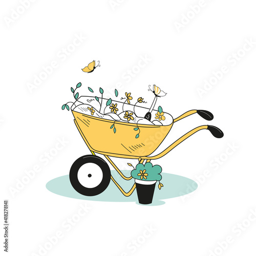 A garden wheelbarrow in the garden with weeds collected in it. Garden tools.