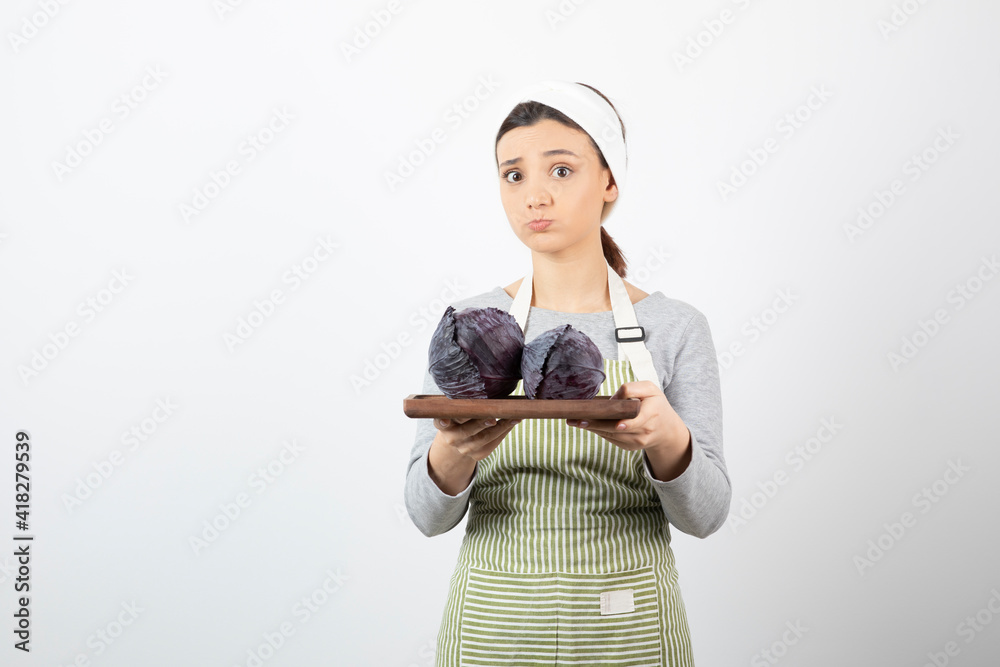 Image of young beautiful housewife holding plate of purple cabbages Image of young beautiful housewife holding plate of purple cabbages