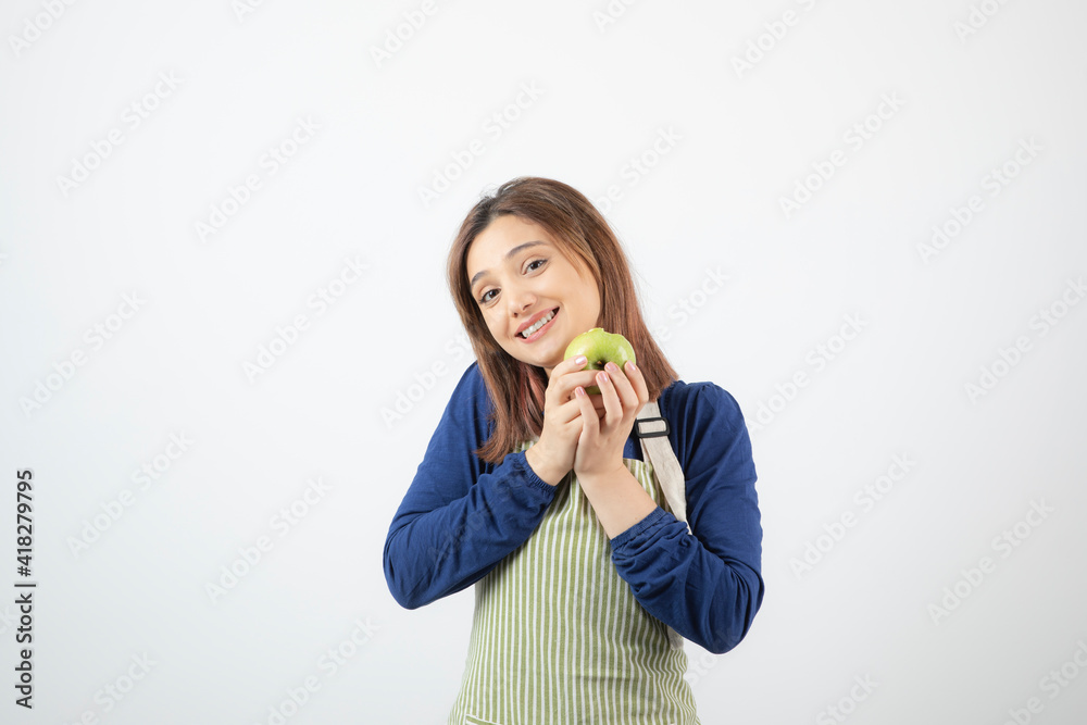 Photo of a cute young woman model in apron holding a green fresh apple Photo of a cute young woman model in apron holding a green fresh apple