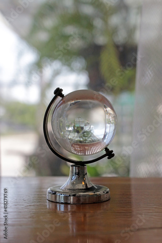 Glass world globe on a shelf in front of a garden window