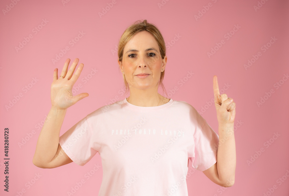 Young woman over pink background smiling and counting six with fingers Young woman over pink background smiling and counting six with fingers