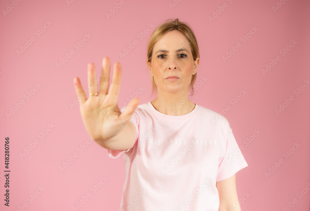 Young woman making stop sign with hand, saying no, looking at camera over pink background. Young woman making stop sign with hand, saying no, looking at camera over pink background.