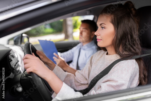 driver courses, exam and people concept - young woman and driving school instructor with clipboard talking in car © Syda Productions