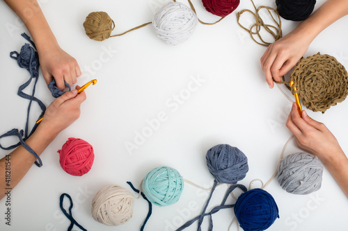 Children's hands are crocheted and thread. View from above