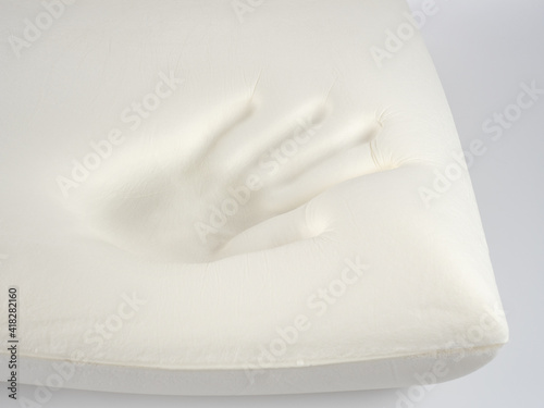 Orthopedic pillow, memory foam. Handprint on the pillow. Comfortable bedding with orthopaedic, therapeutic effect. Memory foam material.