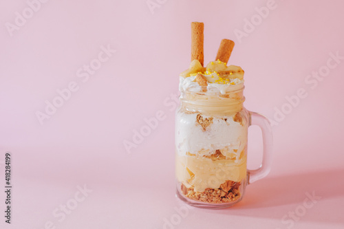 Delicate creamy dessert in a glass on a pink background.