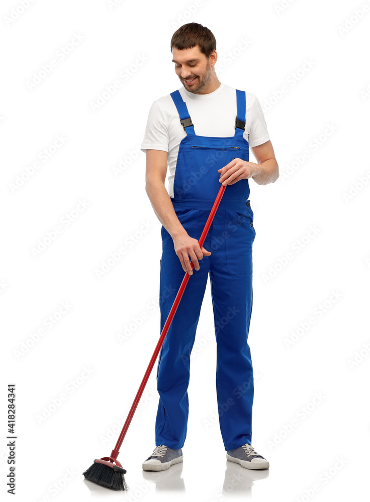 profession, service and people concept - happy smiling male worker or cleaner in overall cleaning floor with broom over white background