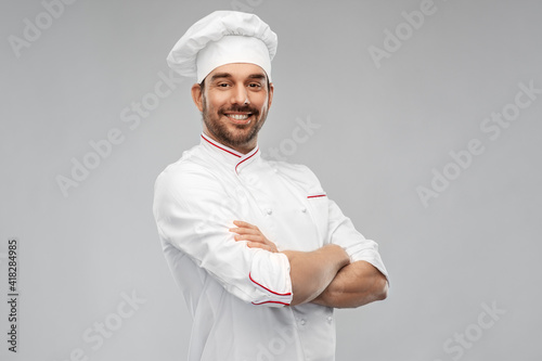 cooking, culinary and people concept - happy smiling male chef in toque and jacket over grey background