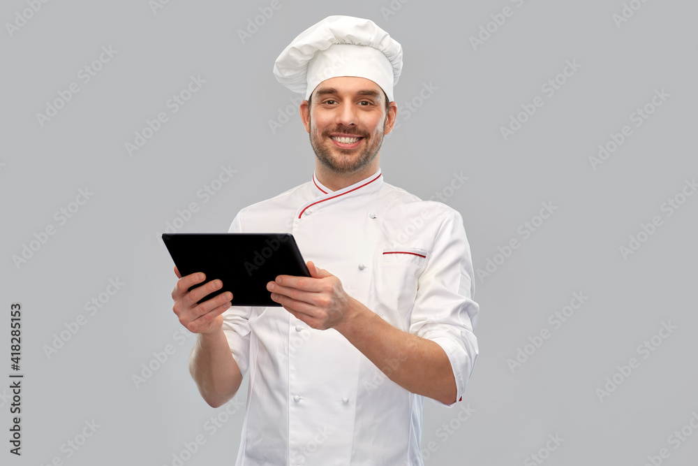 cooking, culinary and people concept - happy smiling male chef in toque with tablet pc computer over grey background cooking, culinary and people concept - happy smiling male chef in toque with tablet pc computer over grey background