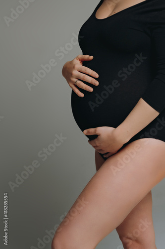 close up photo of pregnant woman belly and her hands touching it.