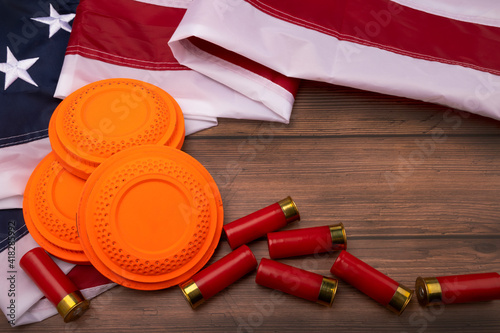 Clay disc flying targets and shotgun bullets with USA flag on wooden background ,Clay Pigeon target