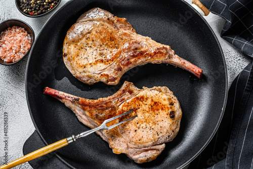 Roasted pork chop meat steak in a pan. White background. Top view