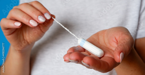 A girl with well-groomed hands holds a hygienic tampon. Close-up.