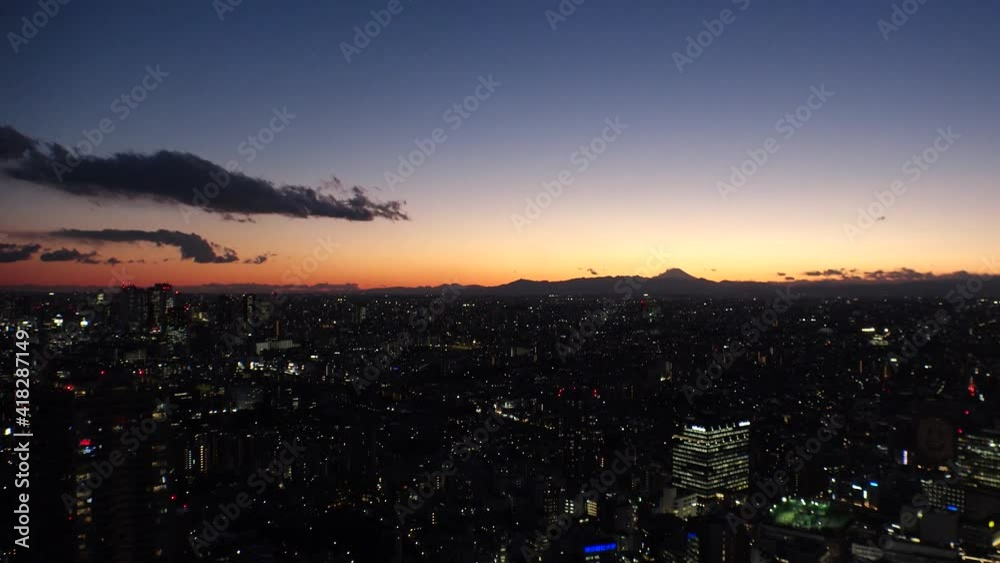 TOKYO, JAPAN : Aerial view of sunset CITYSCAPE and MOUNT FUJI. Sun going down behind mountains. Magic hour or golden hour shot. Japanese city life and nature concept. Time lapse shot dusk to night. TOKYO, JAPAN : Aerial view of sunset CITYSCAPE and MOUNT FUJI. Sun going down behind mountains. Magic hour or golden hour shot. Japanese city life and nature concept. Time lapse shot dusk to night.
