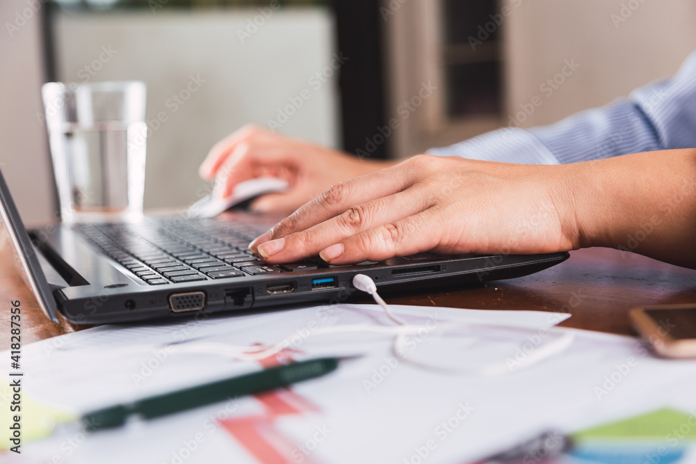 Close-up of hands of a young woman at work typing using a laptop computer.