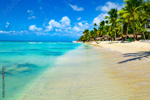 Palm trees, blue sea and sunbeds on Saona Island, Dominican Republic