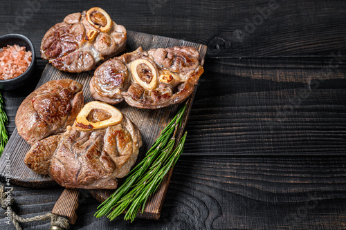 Osso buco cooked Veal shank steak, italian ossobuco. Black wooden background. Top view. Copy space