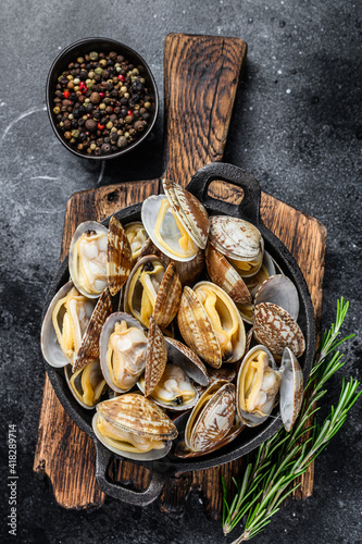 Cooked Clams vongole in a pan. Black background. Top view