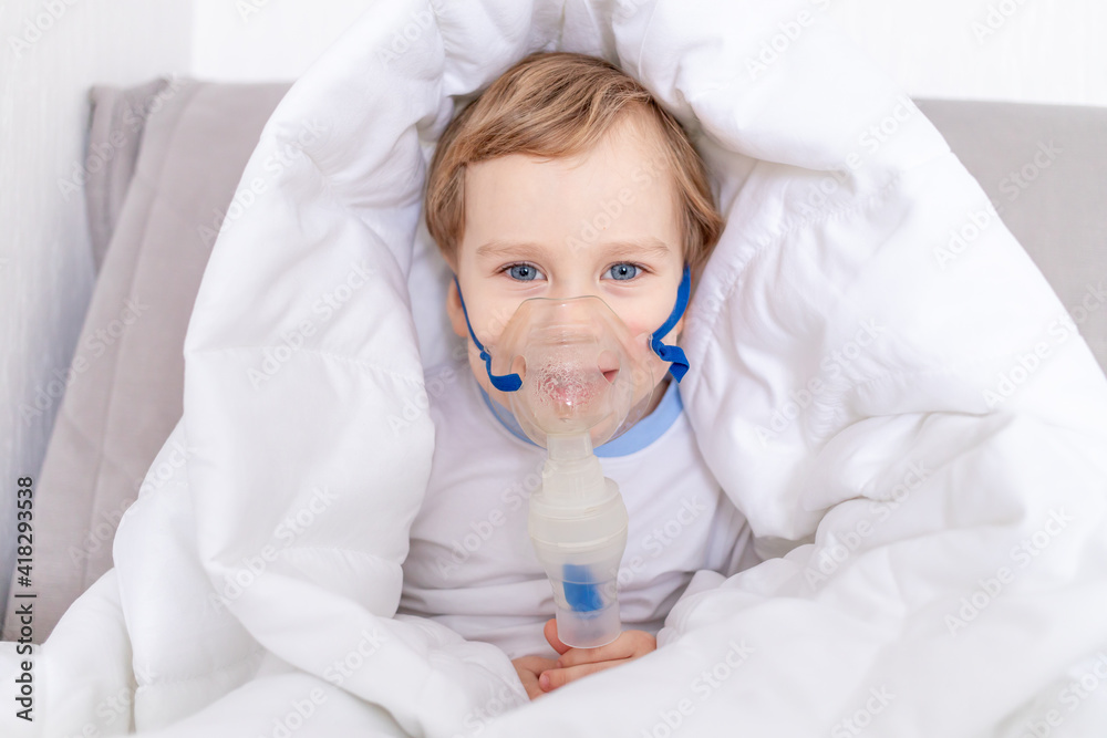 sick baby boy with inhaler treats throat at home, the concept of health and inhalation treatment