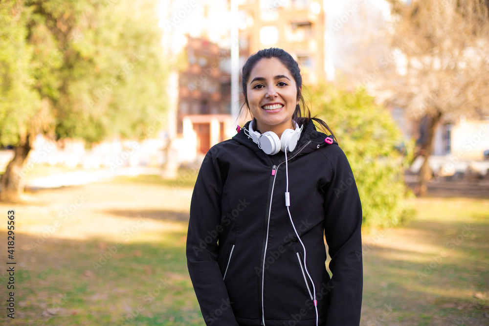 Young brunette sporty girl wearing headphones walking at the park smiling happy and natural Young brunette sporty girl wearing headphones walking at the park smiling happy and natural