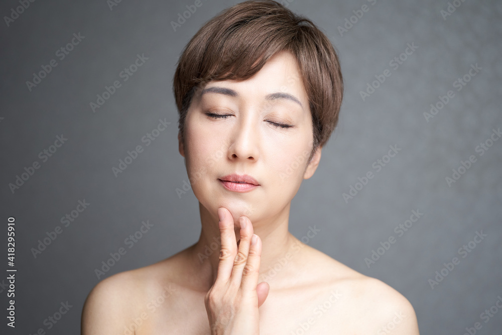 顎に手を当てる目をつぶる中年の日本人女性
