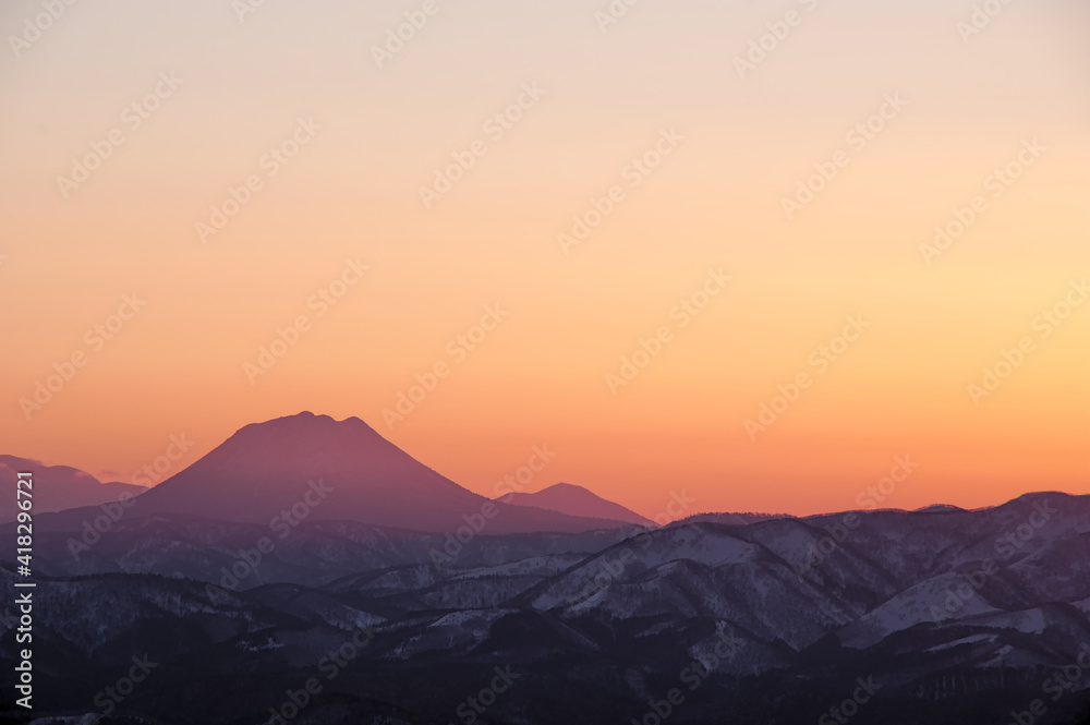 オレンジ色の夕暮れの空と山並みのシルエット。 オレンジ色の夕暮れの空と山並みのシルエット。