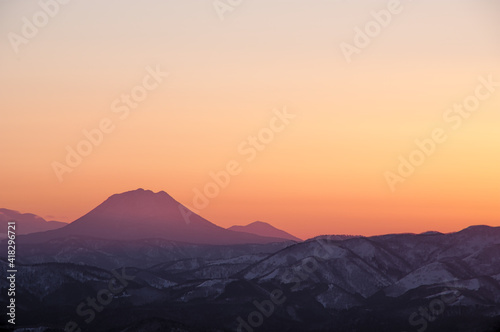 オレンジ色の夕暮れの空と山並みのシルエット。 © Masa Tsuchiya